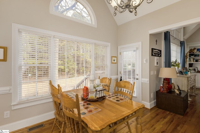 dining space featuring wood-type flooring, plenty of natural light, high vaulted ceiling, and a chandelier