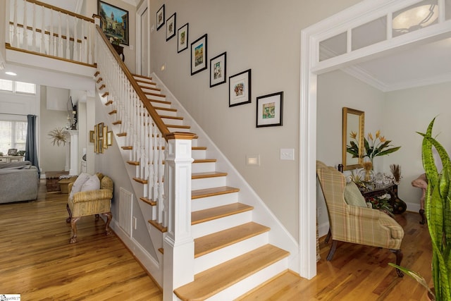 stairs with crown molding, hardwood / wood-style floors, and a high ceiling