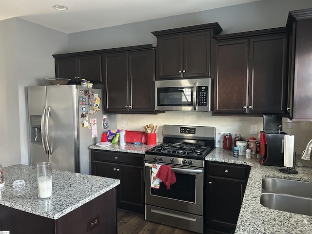 kitchen featuring sink, decorative backsplash, light stone countertops, and appliances with stainless steel finishes