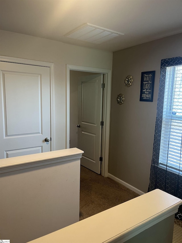 hallway featuring dark colored carpet