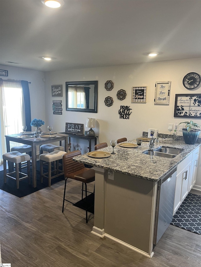 kitchen featuring sink, white cabinetry, dark stone countertops, dark hardwood / wood-style floors, and stainless steel dishwasher