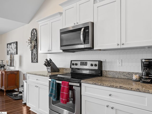 kitchen with lofted ceiling, light stone countertops, white cabinets, and appliances with stainless steel finishes