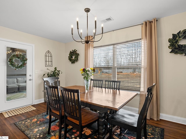 dining space with dark hardwood / wood-style floors and a notable chandelier