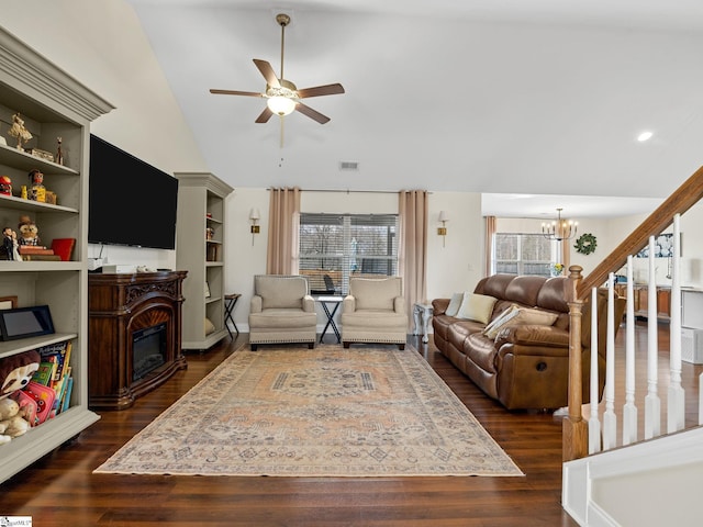 living room with vaulted ceiling, dark wood-type flooring, ceiling fan with notable chandelier, and built in shelves