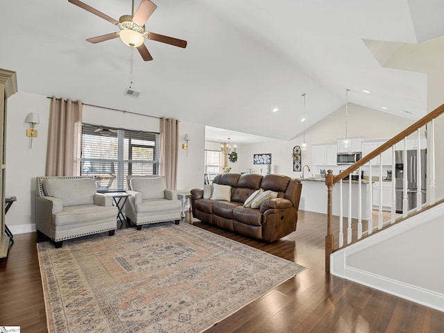 living room featuring dark hardwood / wood-style flooring, sink, ceiling fan with notable chandelier, and vaulted ceiling