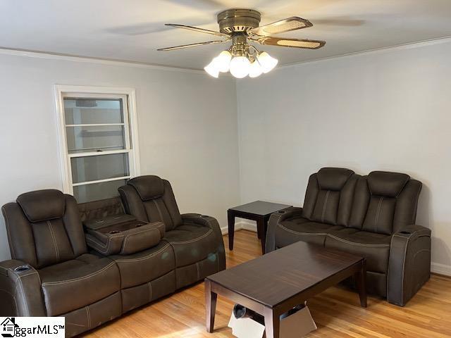 living room with ornamental molding, light hardwood / wood-style floors, and ceiling fan