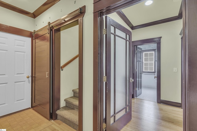 hallway with vaulted ceiling, a barn door, and light hardwood / wood-style floors