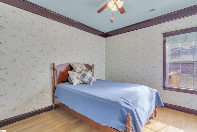 bedroom featuring crown molding, ceiling fan, and light wood-type flooring