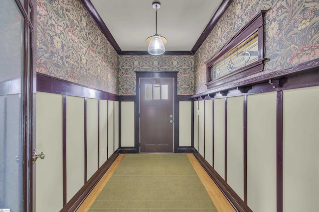 doorway featuring crown molding and light hardwood / wood-style floors