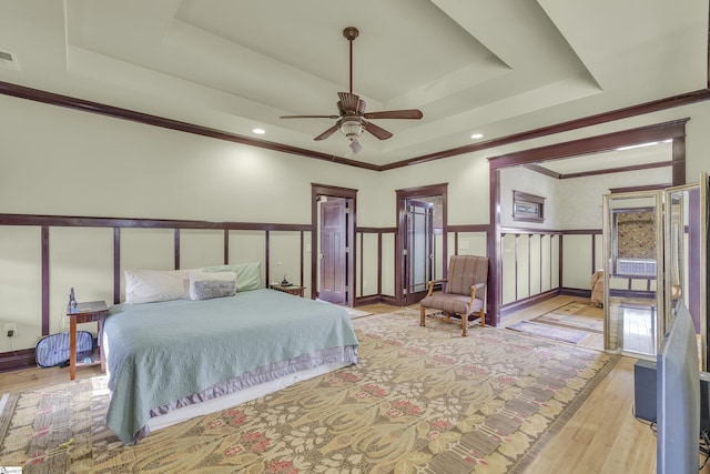 bedroom with a raised ceiling, ceiling fan, and light wood-type flooring