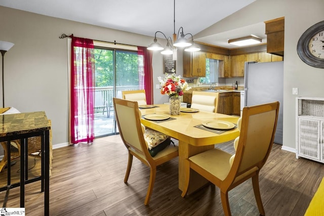 dining room with sink, wood-type flooring, and vaulted ceiling