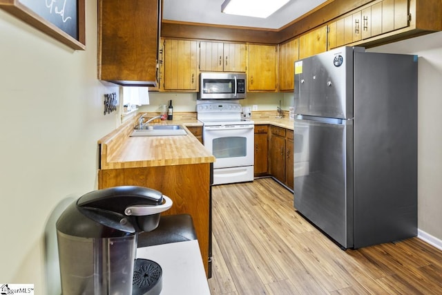 kitchen featuring stainless steel appliances, sink, and light wood-type flooring