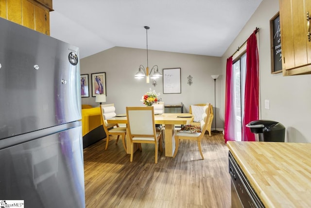 dining area featuring hardwood / wood-style flooring, lofted ceiling, and a notable chandelier