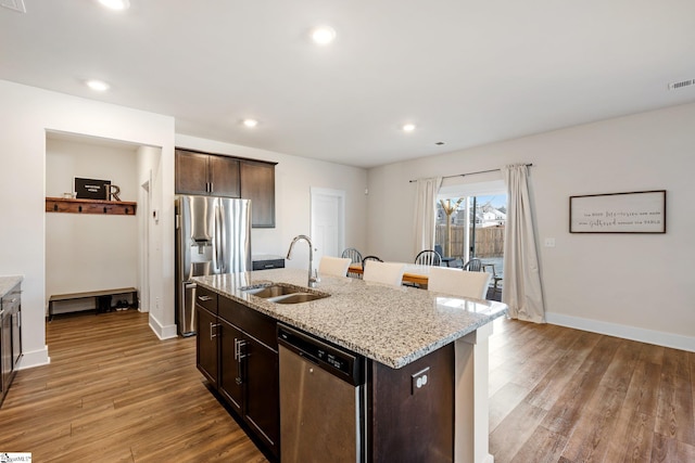 kitchen with stainless steel appliances, a kitchen island with sink, sink, and dark brown cabinetry