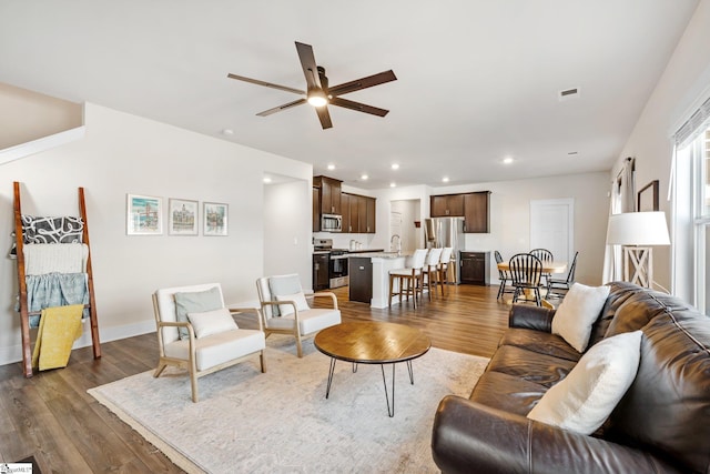 living room featuring ceiling fan, sink, and dark hardwood / wood-style flooring