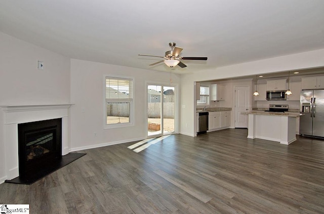 unfurnished living room with dark hardwood / wood-style flooring and ceiling fan