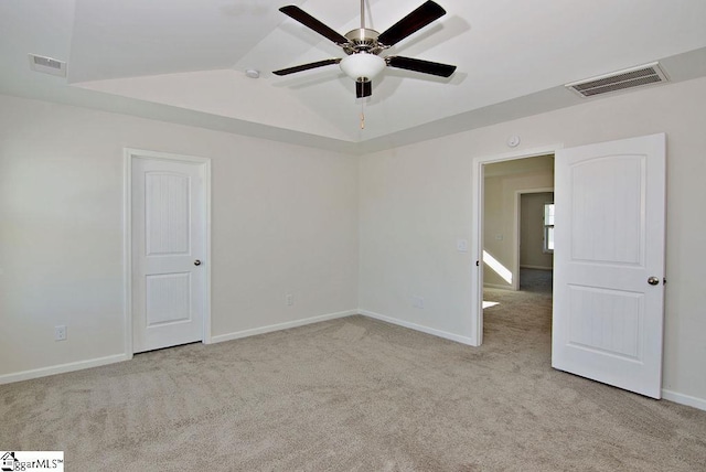 empty room featuring lofted ceiling, light colored carpet, and ceiling fan