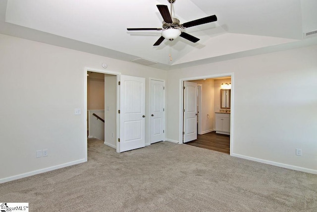 unfurnished bedroom featuring vaulted ceiling, carpet flooring, ensuite bathroom, and ceiling fan