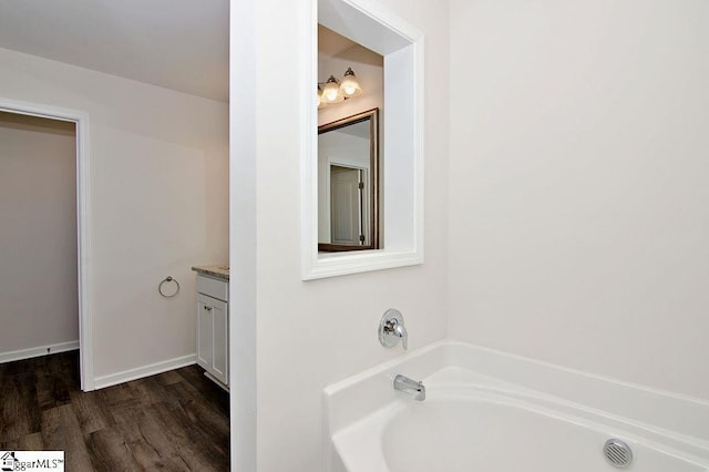 bathroom with vanity, hardwood / wood-style floors, and a tub to relax in