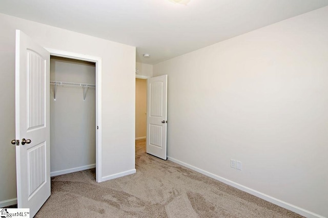 unfurnished bedroom featuring light carpet and a closet