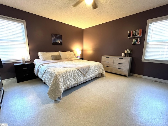 bedroom featuring multiple windows, a textured ceiling, and ceiling fan