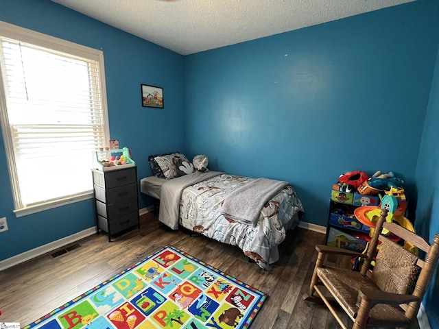 bedroom featuring dark hardwood / wood-style flooring and a textured ceiling