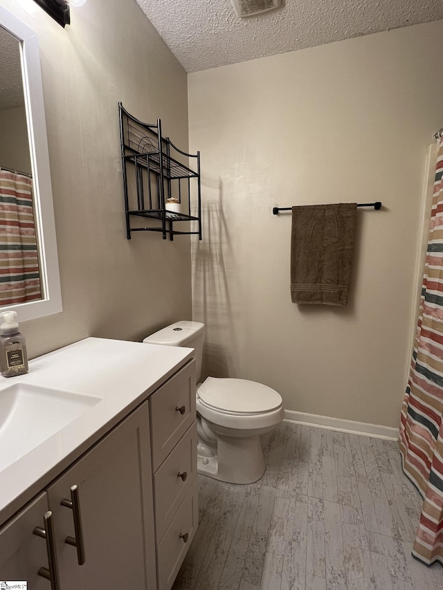 bathroom with hardwood / wood-style flooring, vanity, toilet, and a textured ceiling