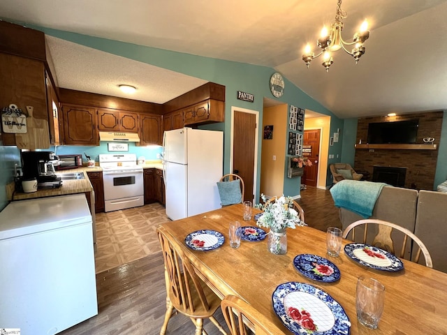 dining room featuring vaulted ceiling, a fireplace, sink, a chandelier, and light hardwood / wood-style floors