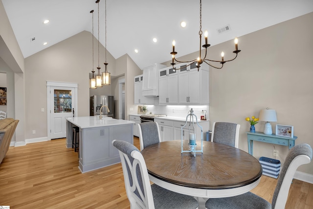 dining area featuring high vaulted ceiling, sink, and light hardwood / wood-style floors