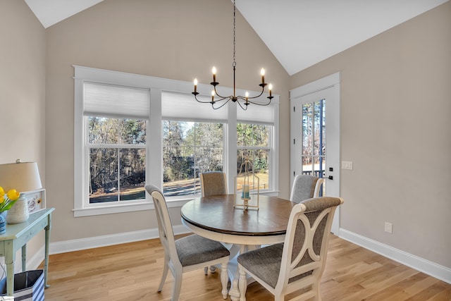 dining room featuring lofted ceiling, a chandelier, a wealth of natural light, and light hardwood / wood-style floors