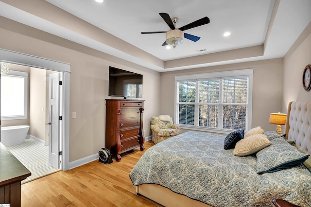 bedroom featuring a tray ceiling, ceiling fan, and light wood-type flooring