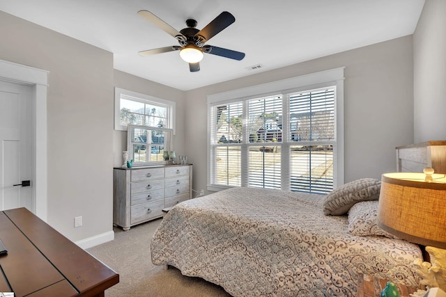 bedroom with multiple windows, light colored carpet, and ceiling fan