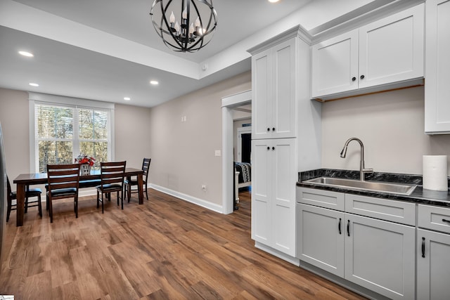 kitchen featuring sink, white cabinetry, a chandelier, hanging light fixtures, and hardwood / wood-style flooring