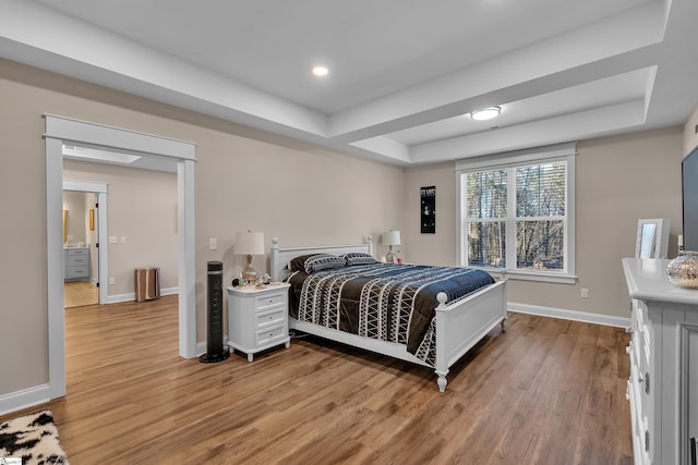 bedroom featuring a raised ceiling and light wood-type flooring