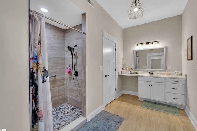 bathroom featuring a tile shower, vanity, and hardwood / wood-style floors