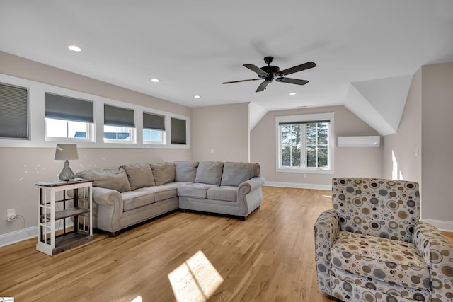 living room featuring ceiling fan, an AC wall unit, lofted ceiling, and light wood-type flooring