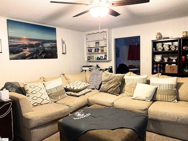 living room with ceiling fan, a textured ceiling, and wood walls