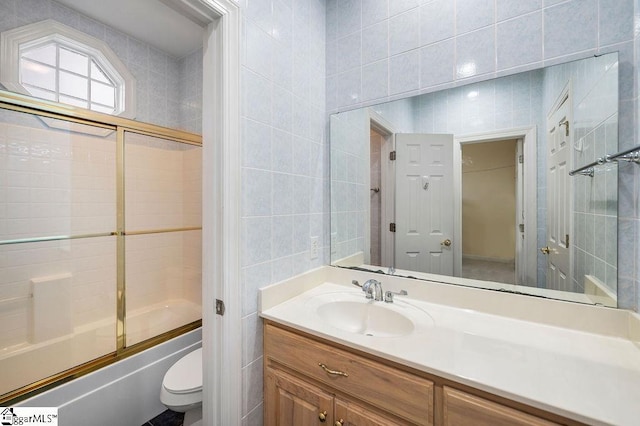 full bathroom with enclosed tub / shower combo, tile walls, vanity, and toilet