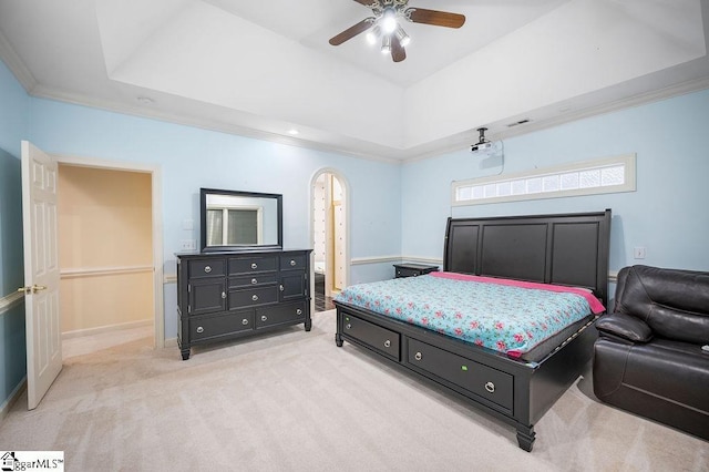 carpeted bedroom with ceiling fan, ornamental molding, and a tray ceiling