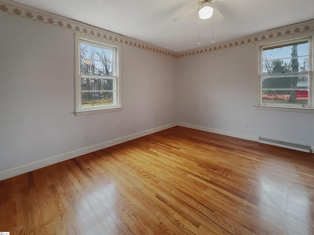 unfurnished room featuring a baseboard heating unit, light hardwood / wood-style flooring, and ceiling fan