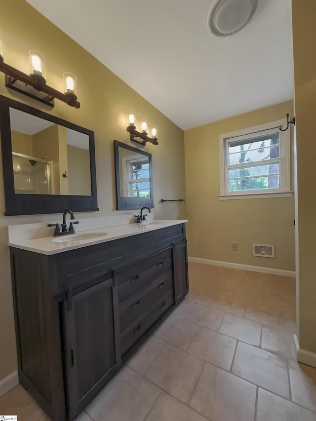 bathroom with a shower with door, vanity, and tile patterned floors