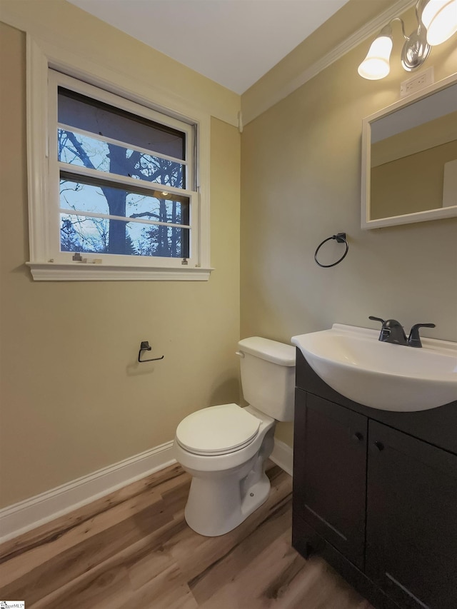 bathroom featuring wood-type flooring, vanity, crown molding, and toilet