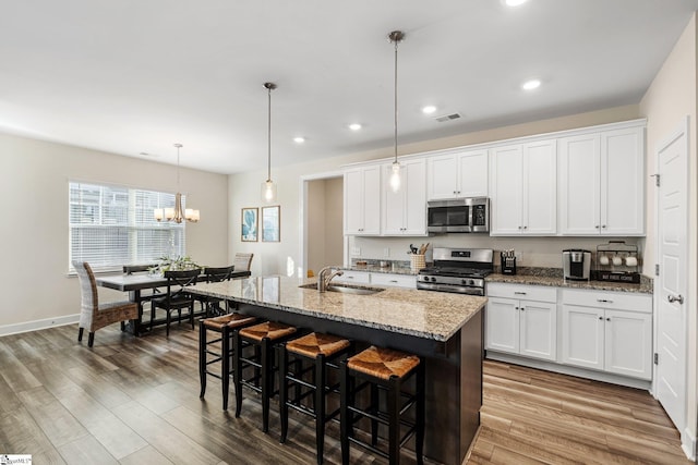 kitchen featuring appliances with stainless steel finishes, a center island with sink, and white cabinets