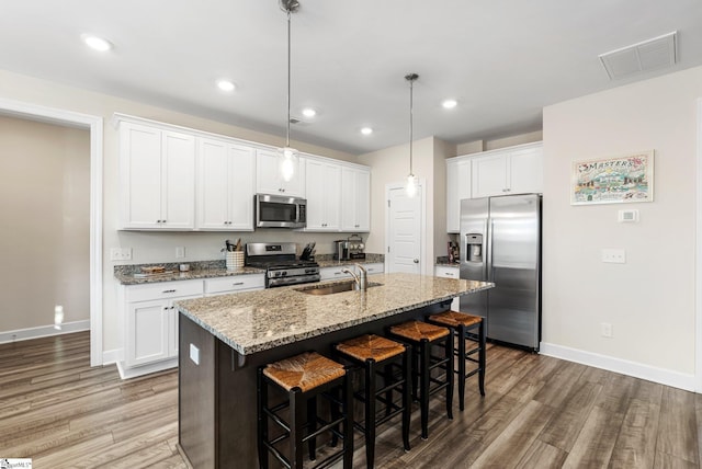 kitchen featuring sink, white cabinetry, decorative light fixtures, an island with sink, and stainless steel appliances