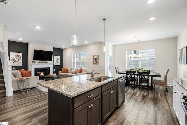 kitchen featuring pendant lighting, sink, dishwasher, dark brown cabinetry, and light stone counters