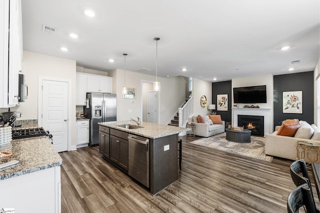 kitchen featuring pendant lighting, white cabinetry, sink, a kitchen island with sink, and stainless steel appliances