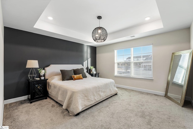 bedroom featuring a tray ceiling and light carpet