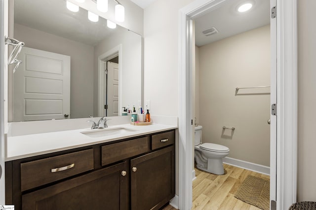 bathroom with wood-type flooring, vanity, and toilet