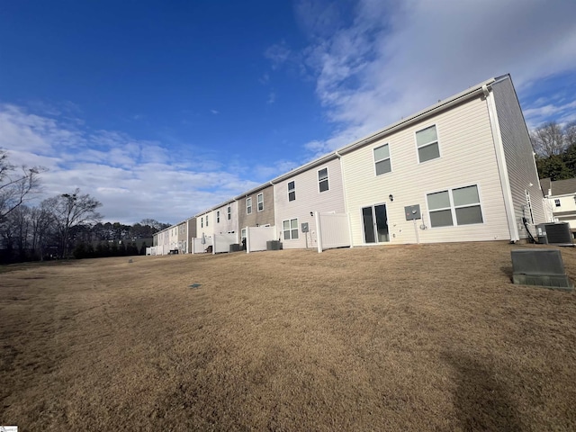 back of house with central AC and a lawn