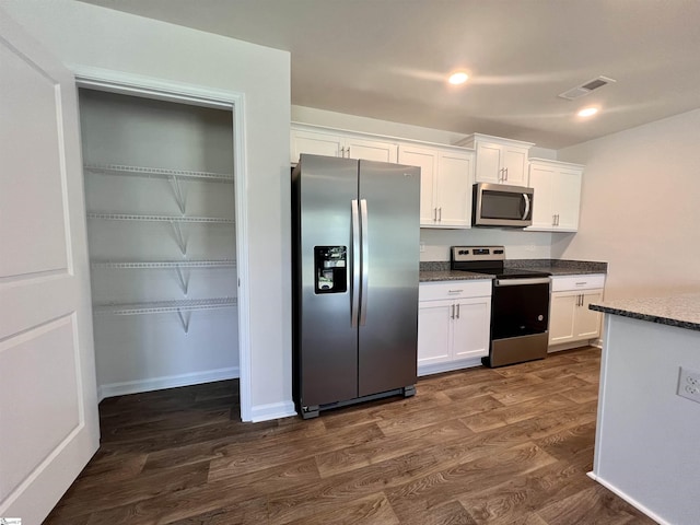 kitchen with stainless steel appliances, dark wood-type flooring, dark stone countertops, and white cabinets